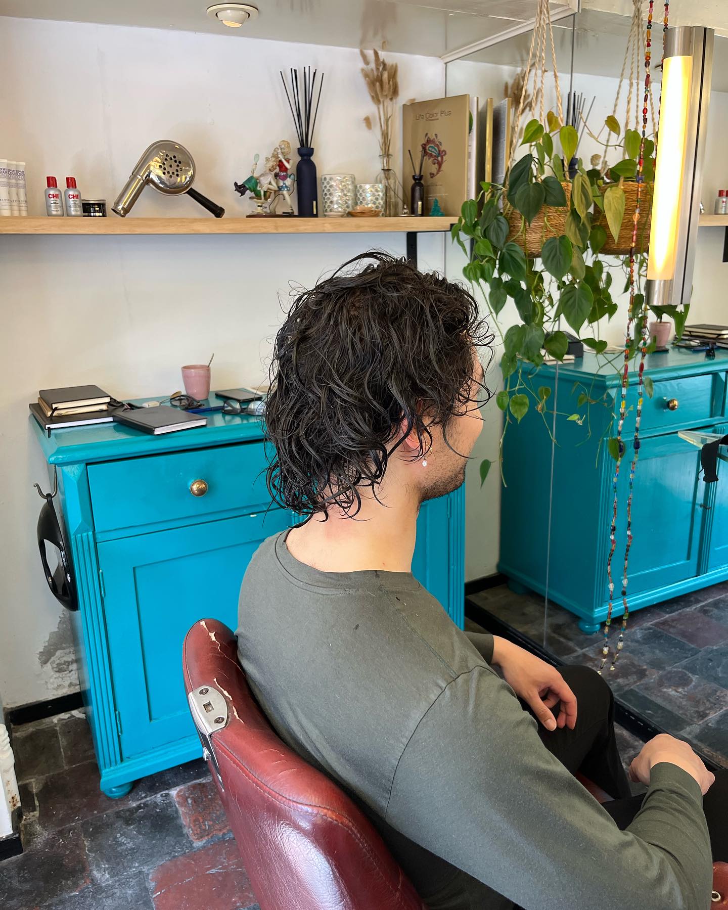 Voor: een klant met lang krullend haar, van opzij gezien in de salon